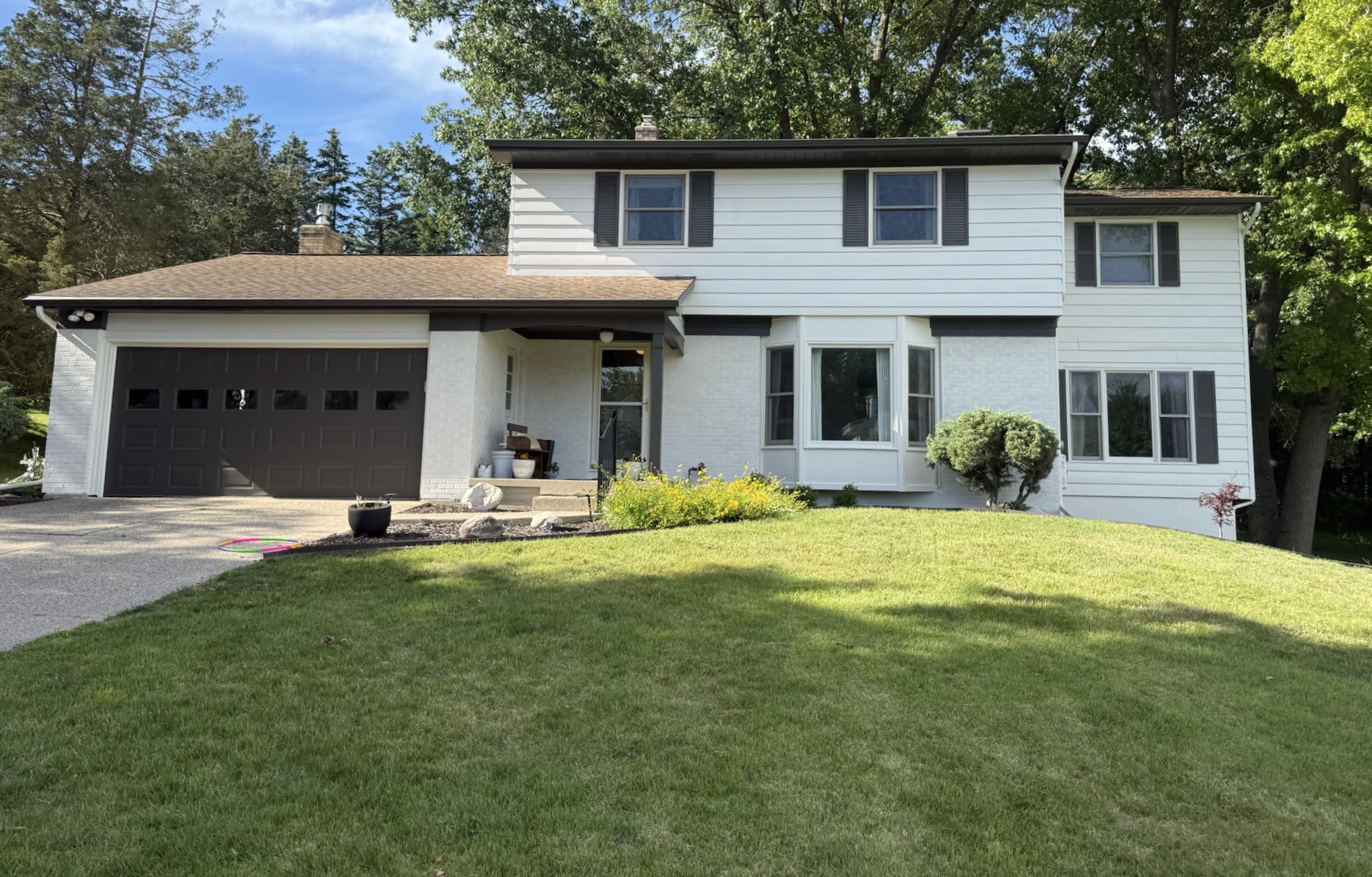 Exterior house after full repaint — crisp white siding with dark shutters and garage door, Grand Rapids MI
