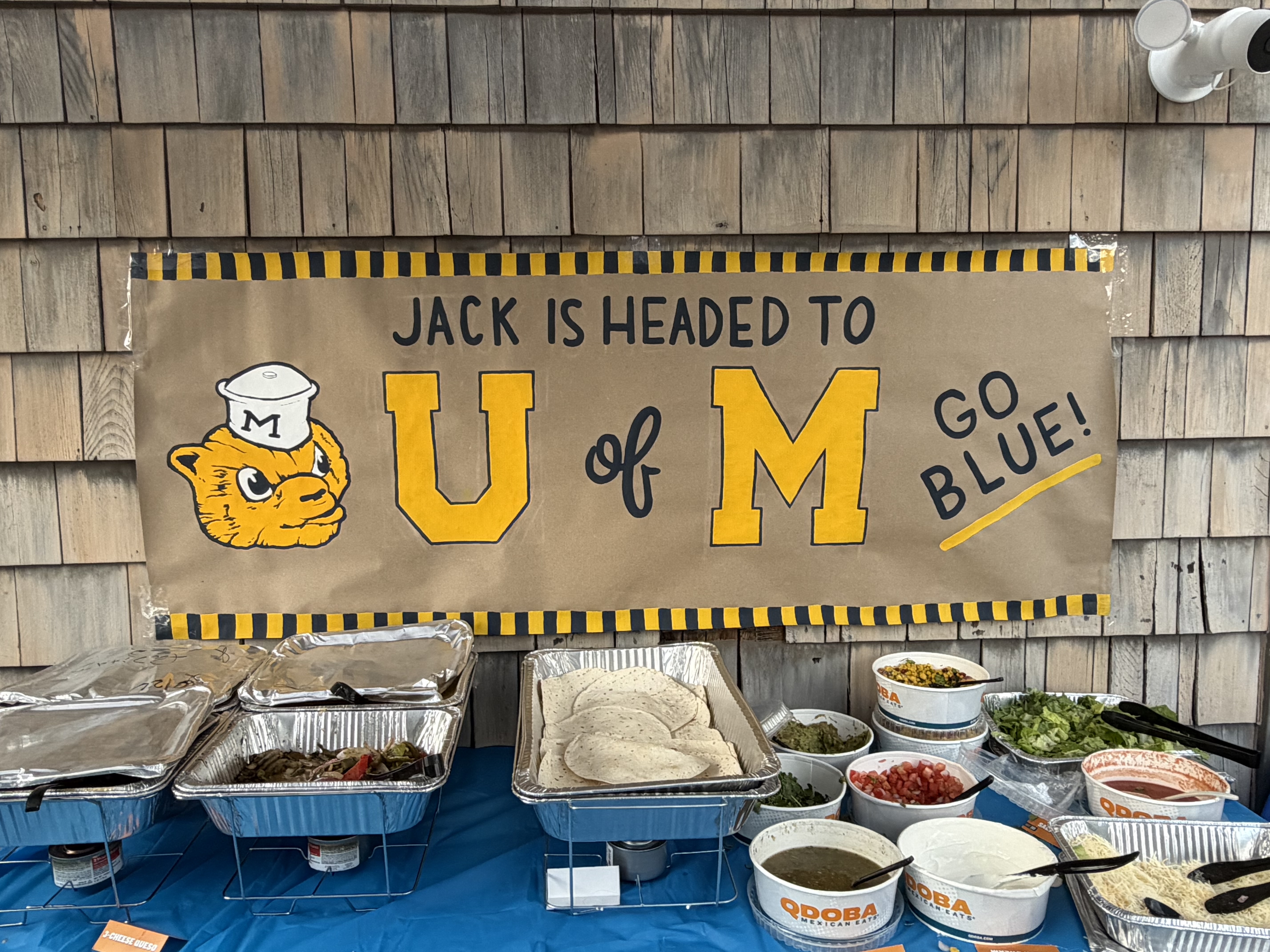 Jack is Headed to U of M Go Blue hand-painted banner displayed at an outdoor graduation party food table