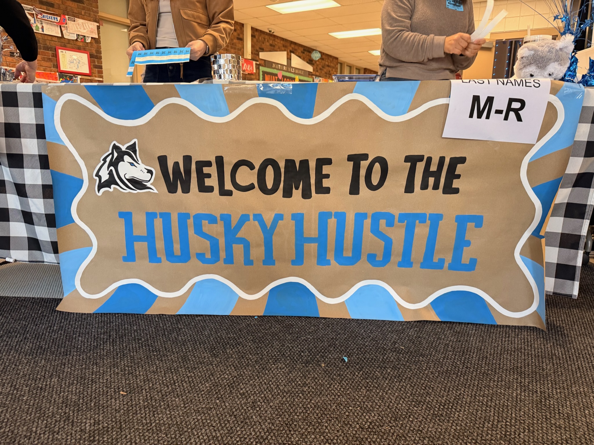 Welcome to the Husky Hustle hand-painted banner on a table at a school event