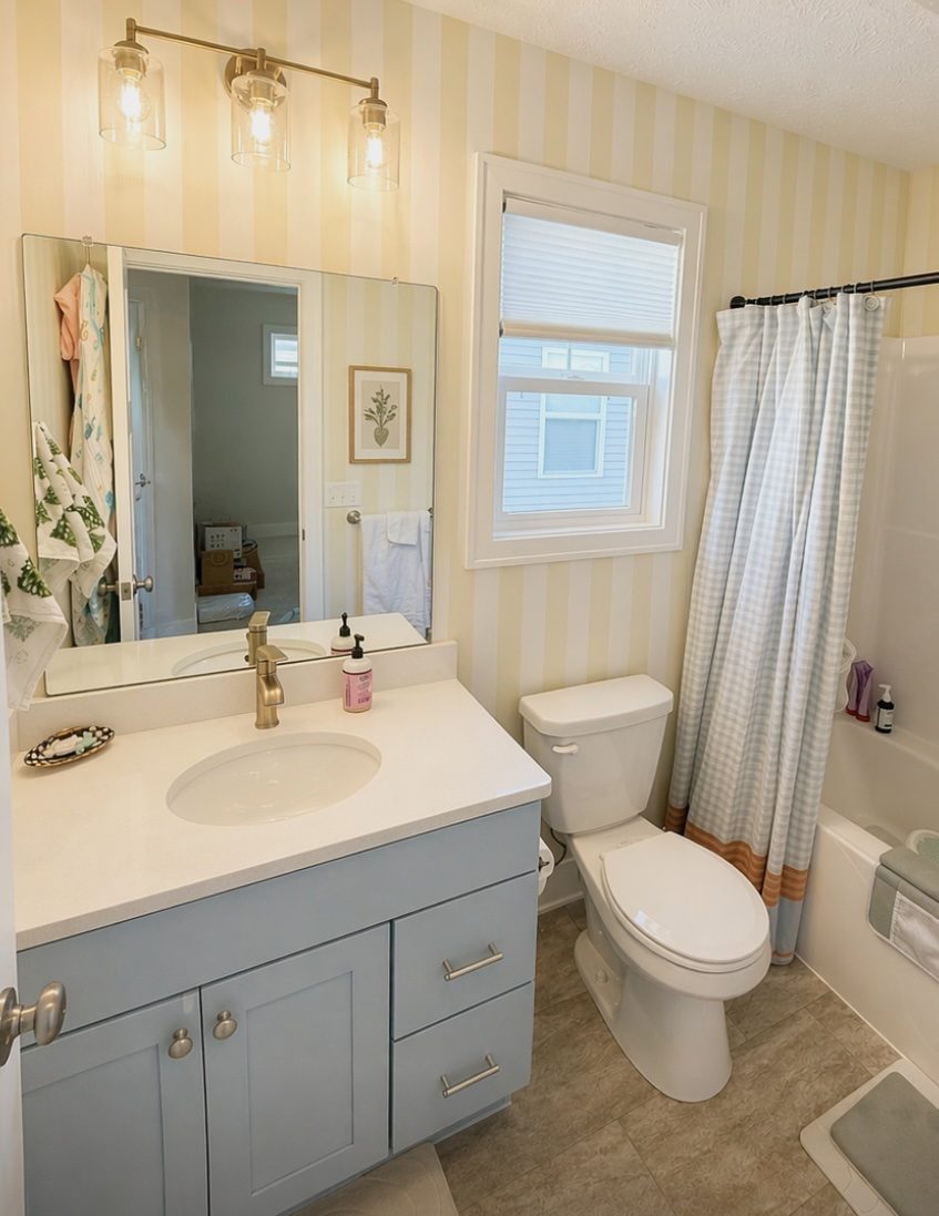 Bathroom after custom yellow stripe wall treatment and blue cabinet refinishing by Go Green College Painters, Grand Rapids MI