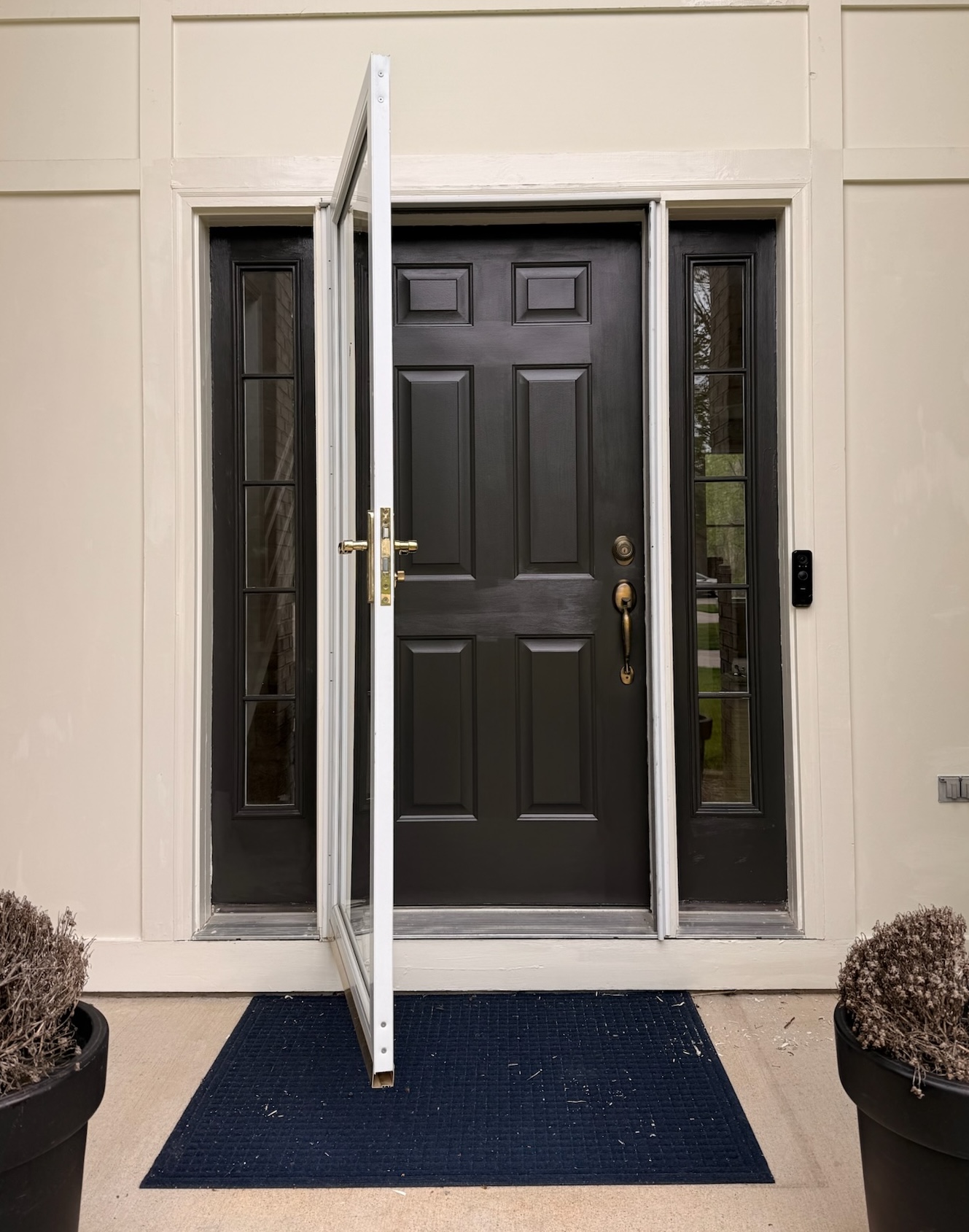 Front door after painting — dramatic matte black door and sidelights, Grand Rapids MI
